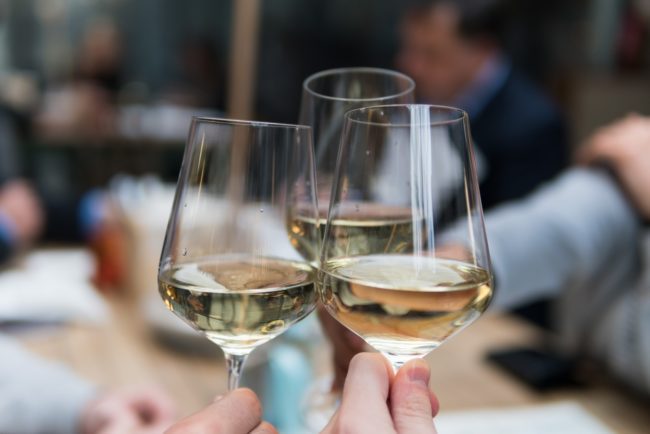 three people having a toast using three clear crystal wine glasses